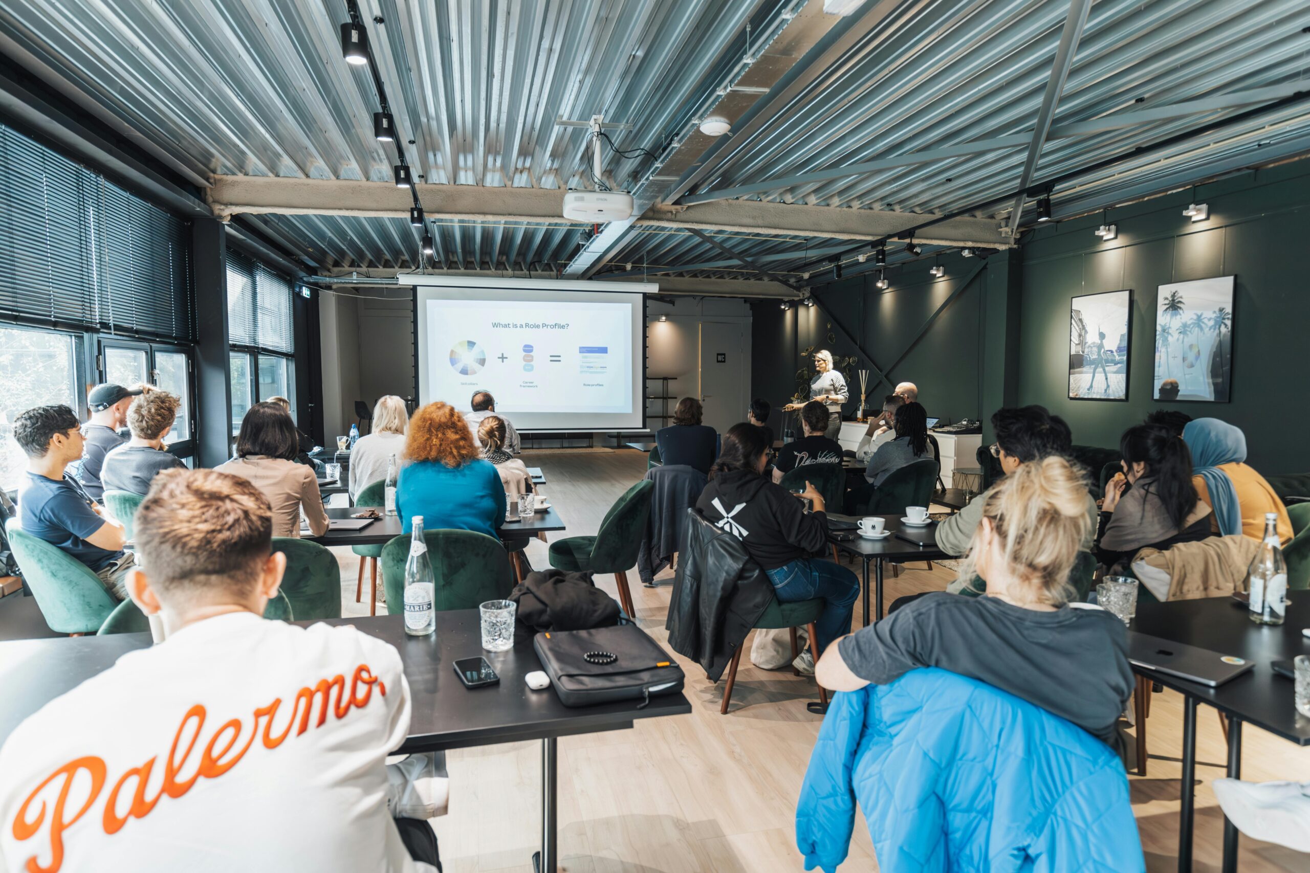 A diverse group attending an educational workshop indoors, focused on a presentation.