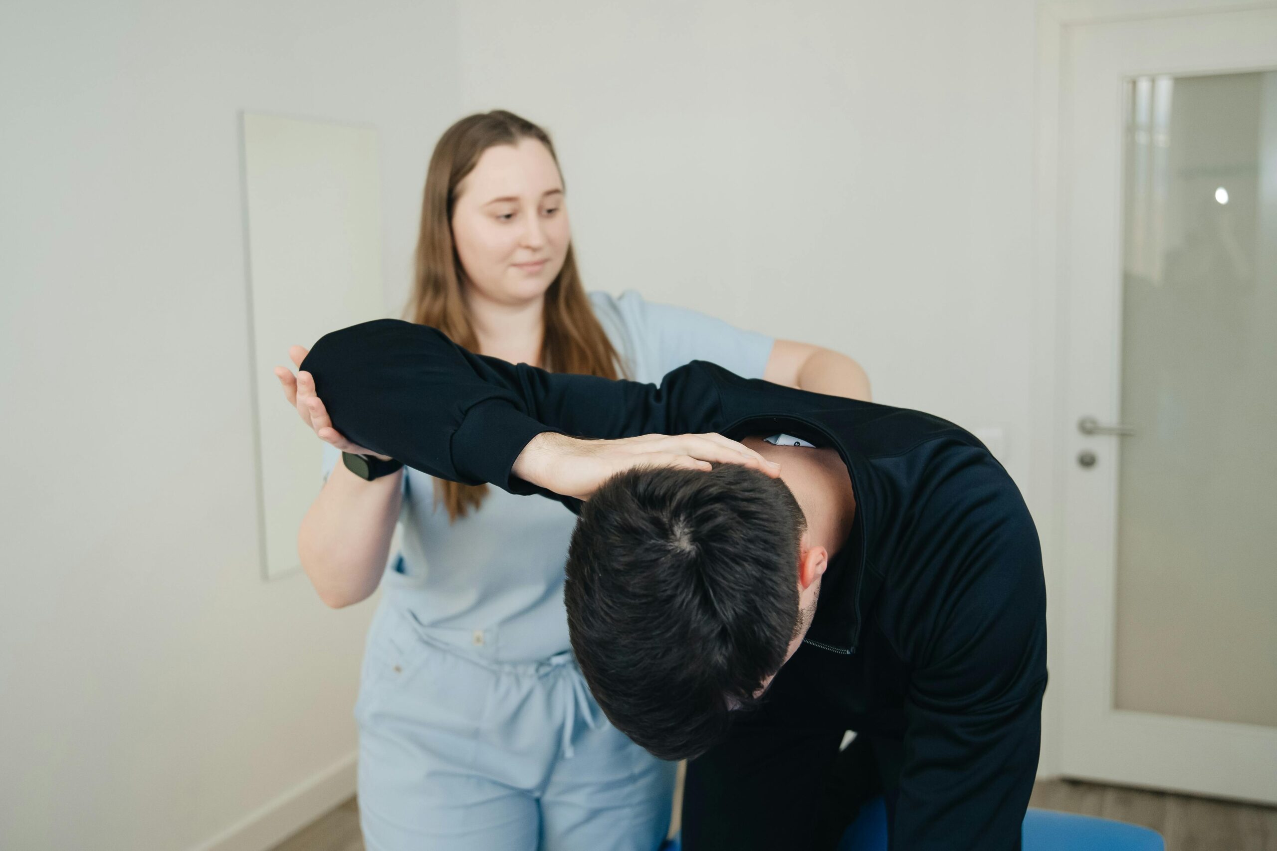 A physiotherapist aids a patient in a stretching exercise for rehabilitation.