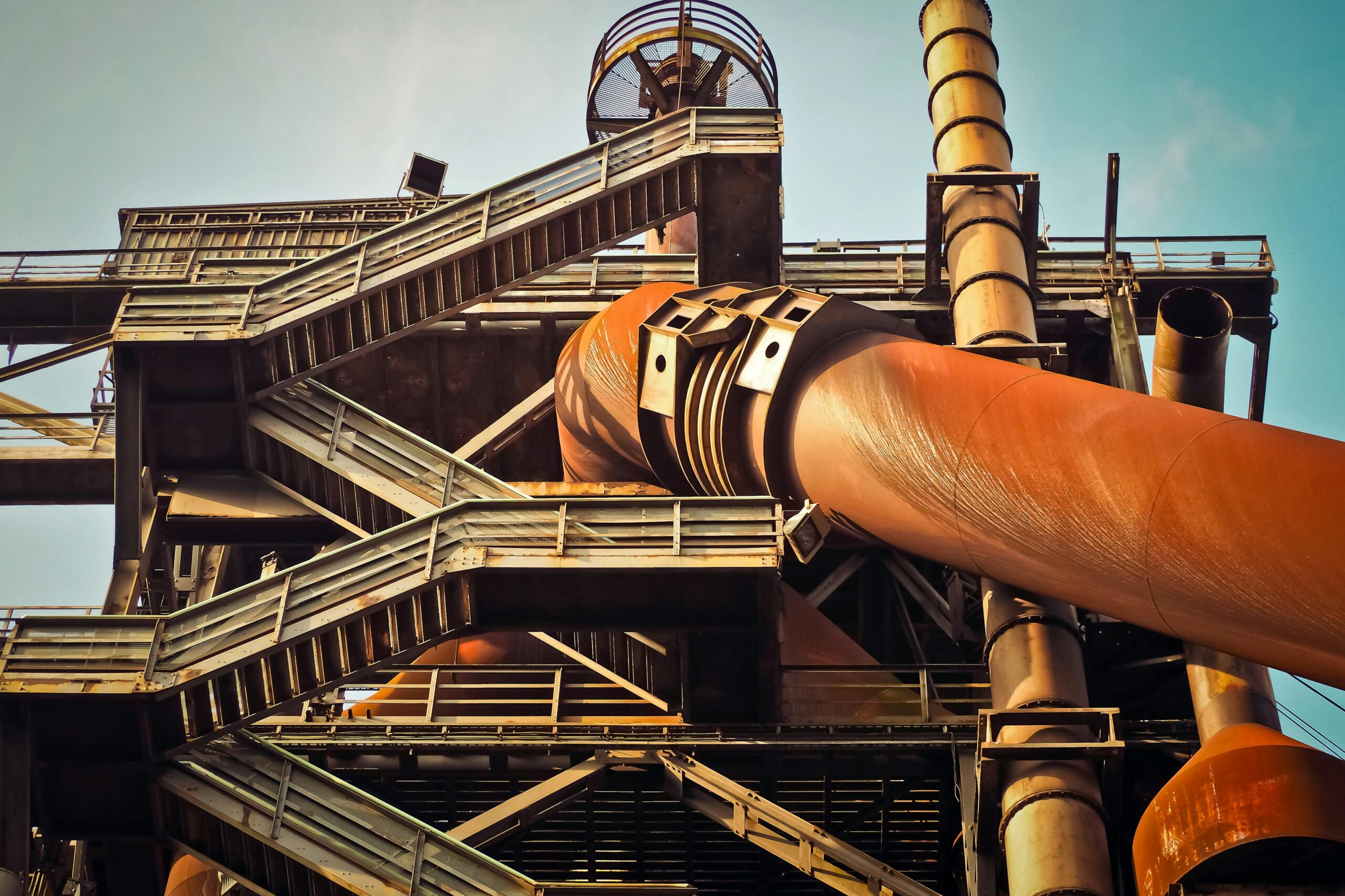 Close-up view of a rusty industrial structure with large pipes and steel framework, showcasing industrial decay.