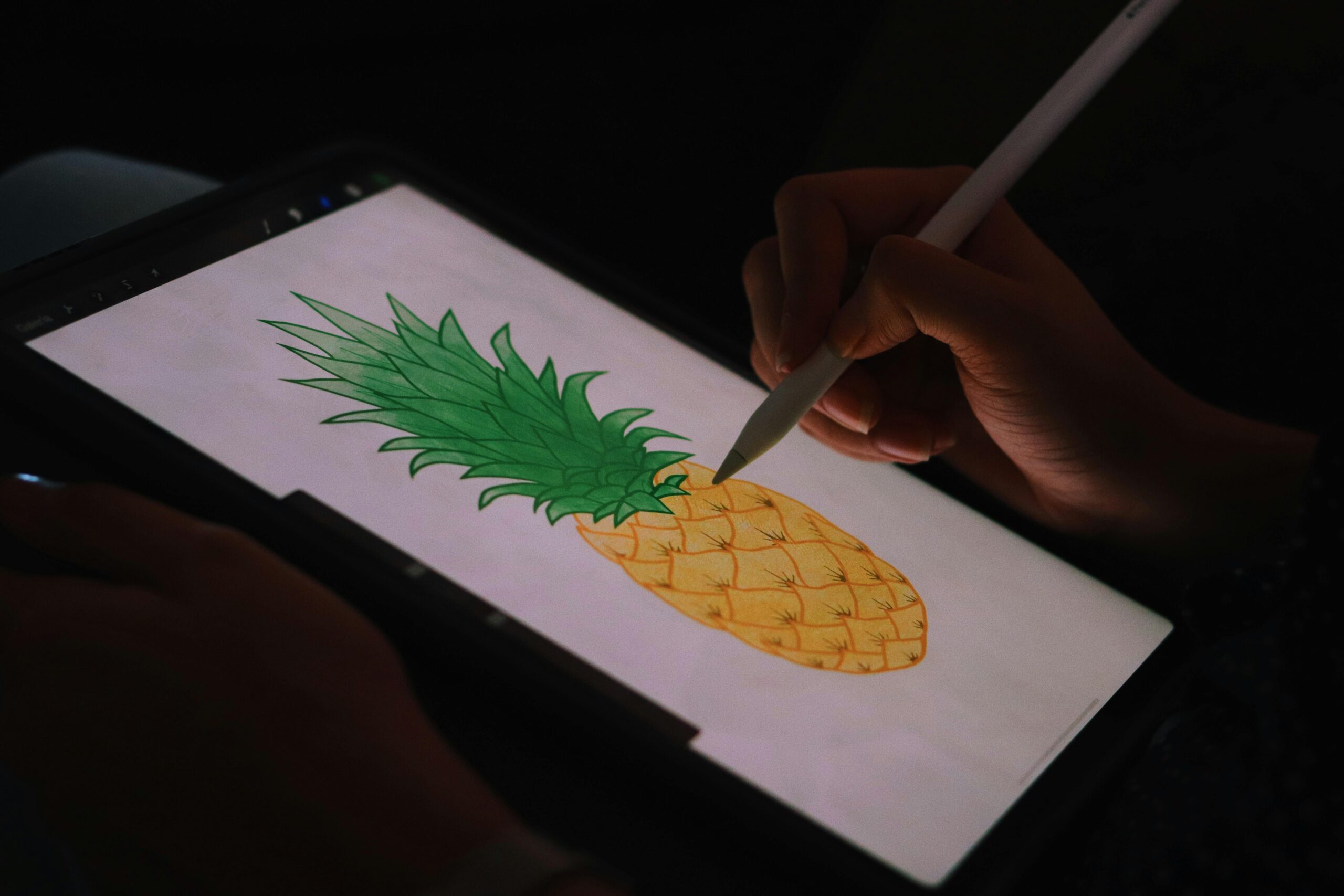 Close-up of a hand drawing a pineapple on a digital tablet.