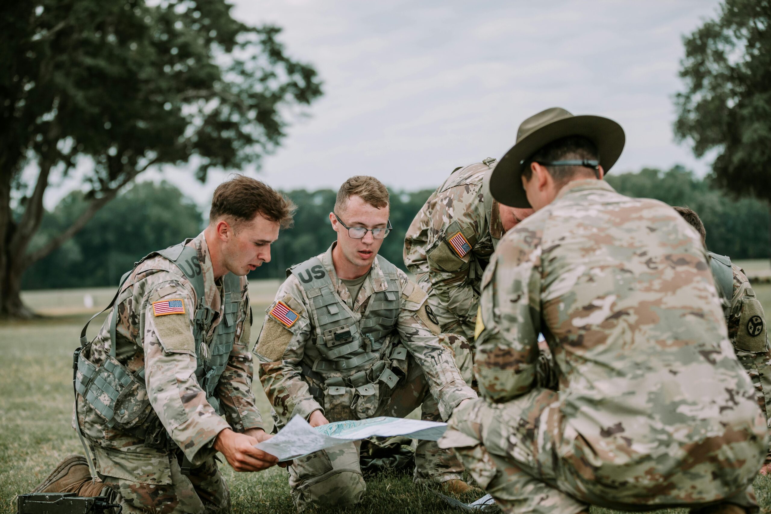 U.S. soldiers in camo gear analyze a map at Fort Moore, GA during drill.