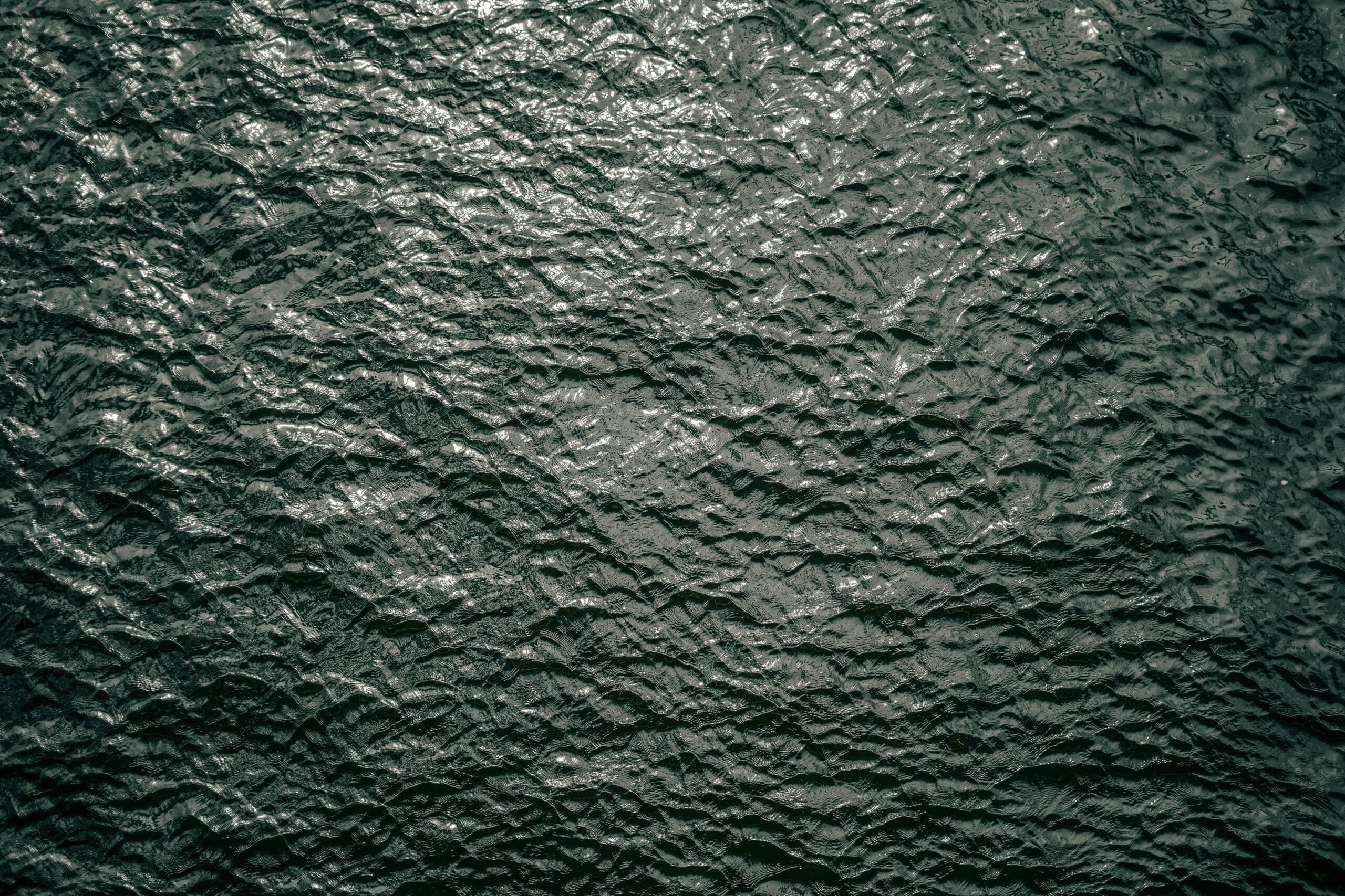 High-resolution image of rippling dark water surface texture, captured outdoors in Berlin, Germany.