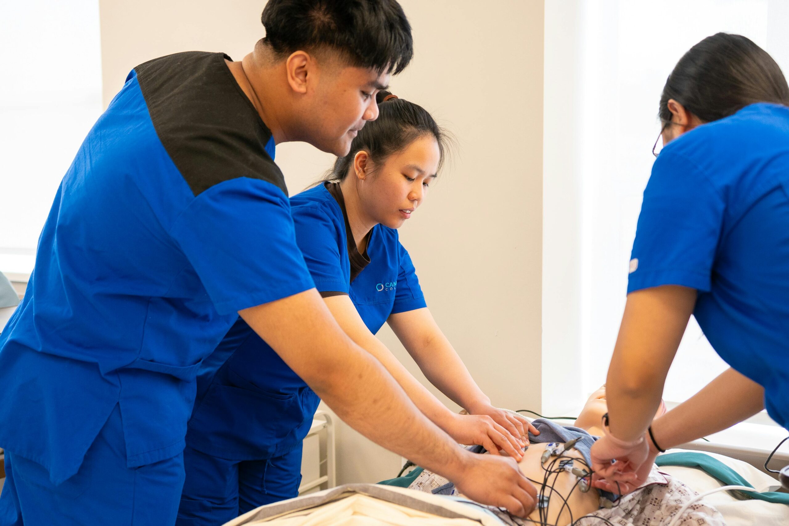 Group of nursing students conducting a medical procedure in a training room.
