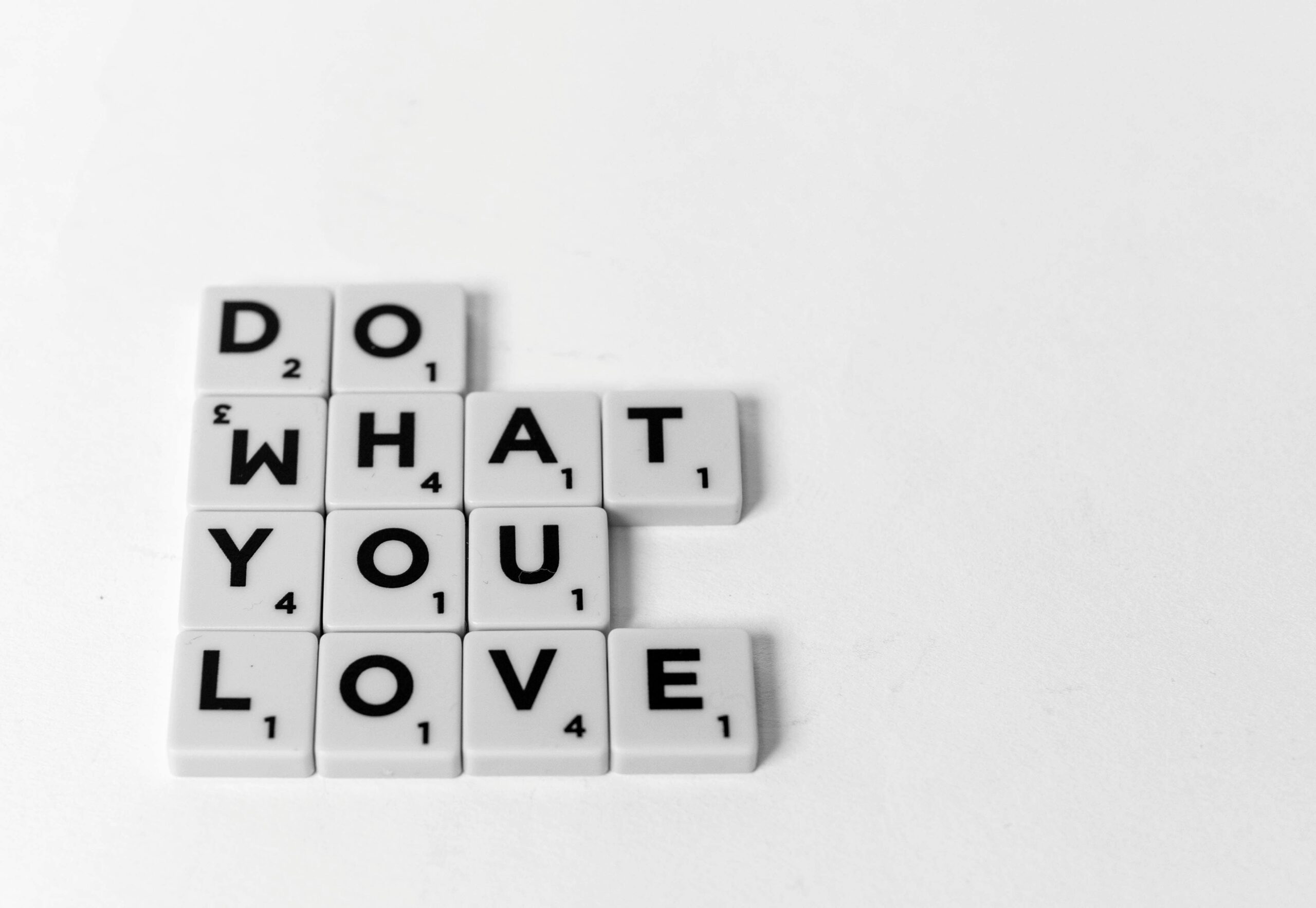 Scrabble tiles spelling 'Do What You Love'. Motivational and creative concept visual.