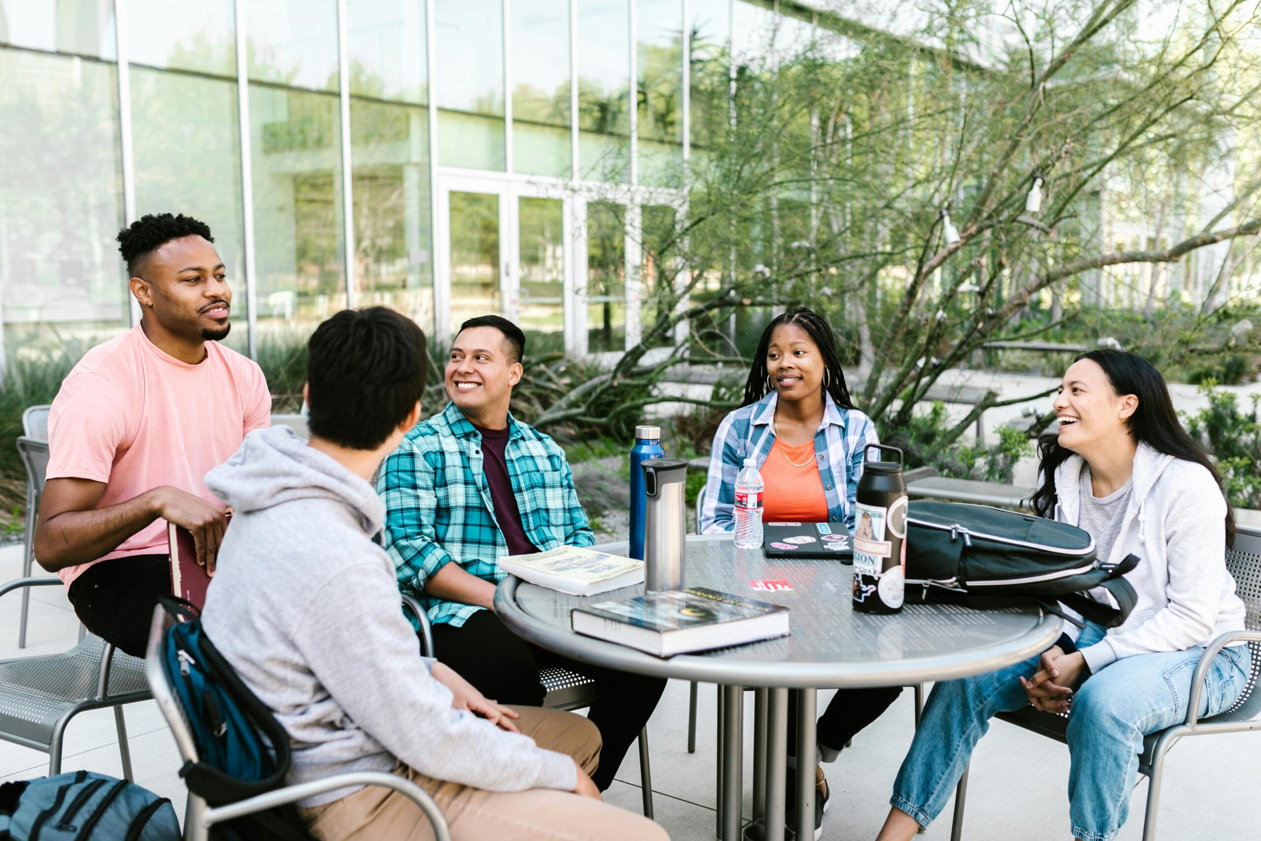 University students studying together outside at a campus table.