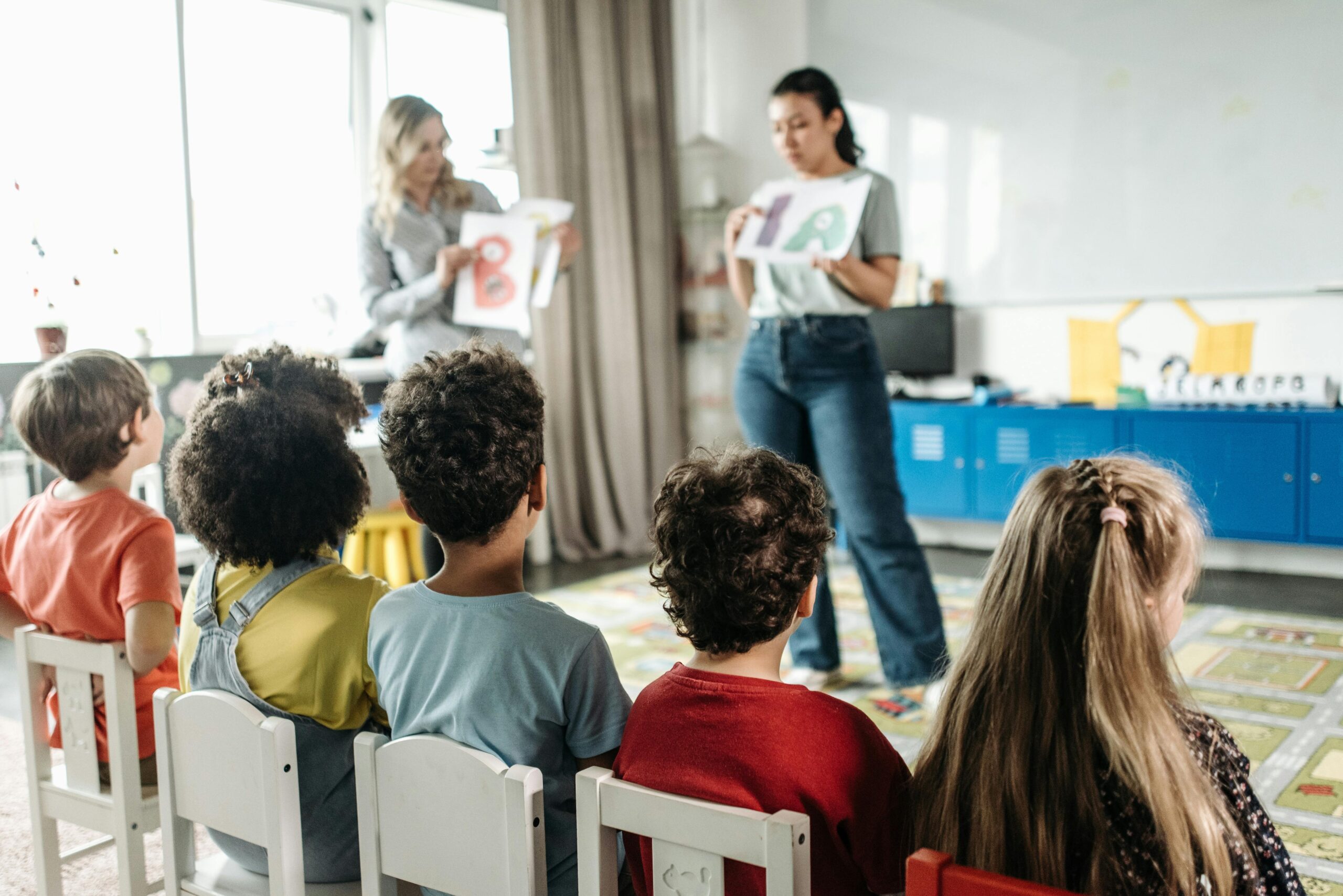 Children in a kindergarten classroom engaging with letters during a learning session.