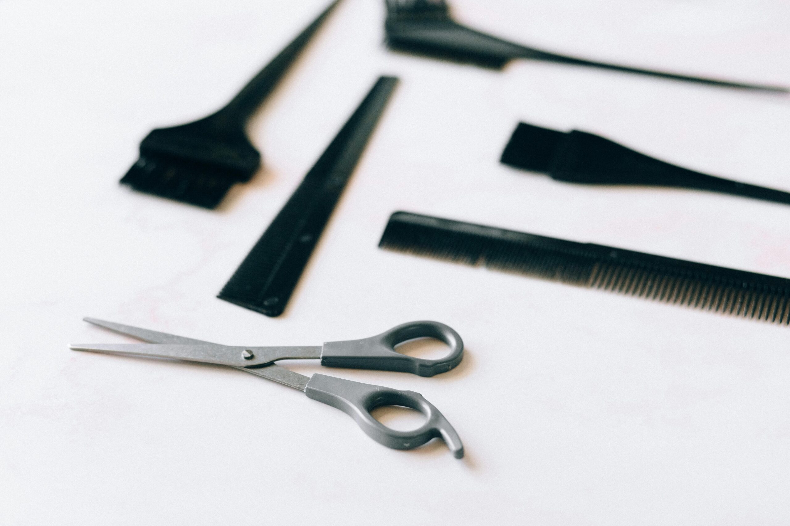 A collection of essential hairdressing tools including scissors and combs on a white surface.