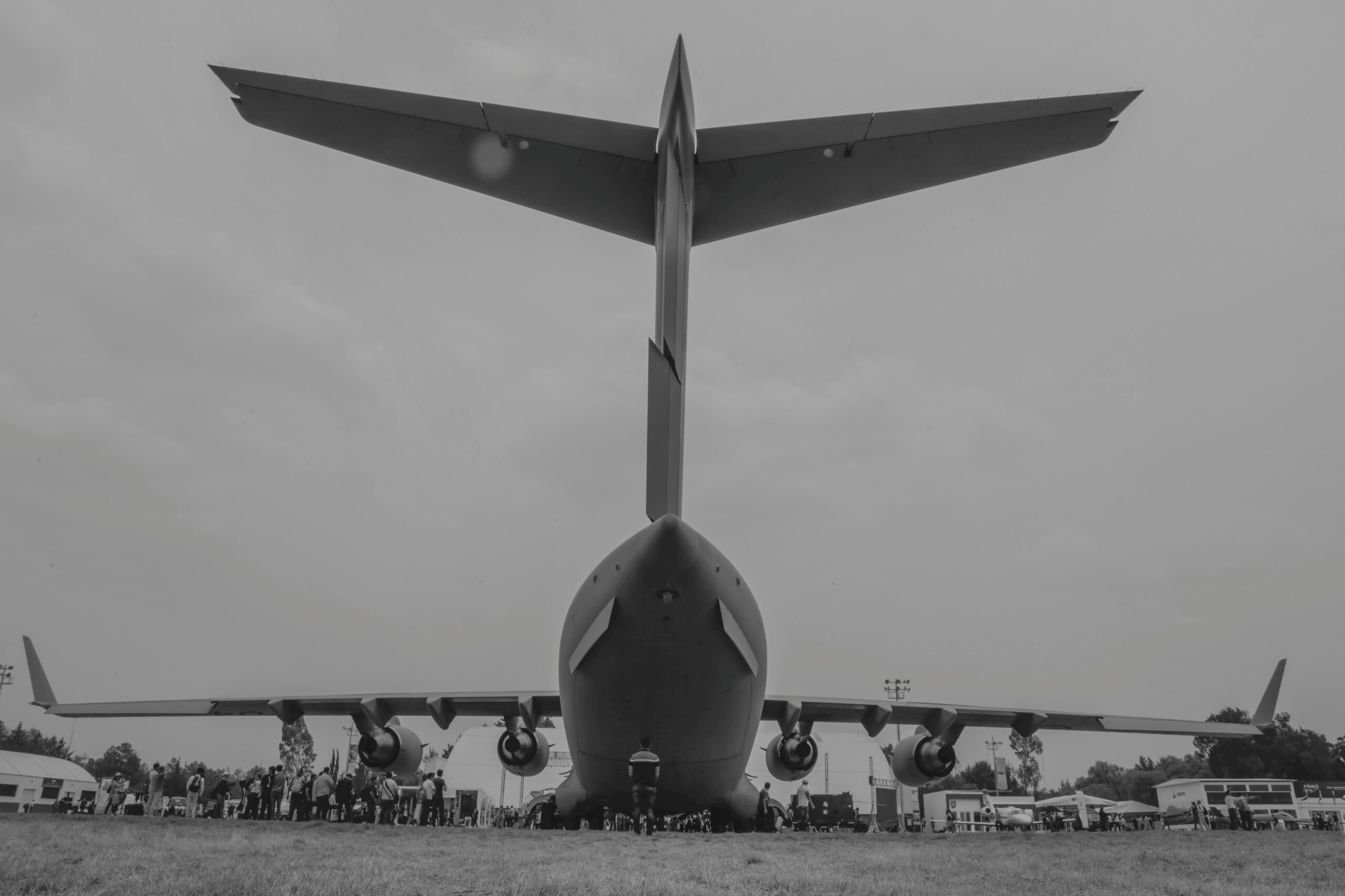 Black and white rear view of a large military aircraft on display outdoors.